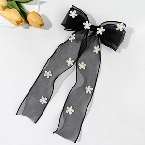 Détail d'un nœud à cheveux en maille noire avec broderie marguerite et longs rubans fluides