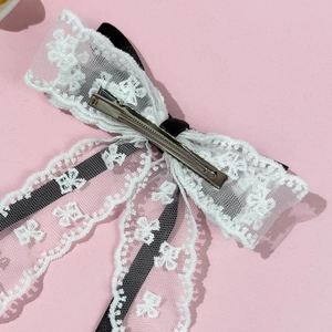 Barrette à cheveux en dentelle florale avec ruban noir sur un fond rose élégant