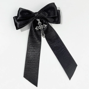 Detail view of black satin bow hair clip featuring a silver gothic cross pendant
