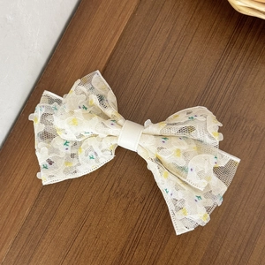 Détail de la pince à cheveux en dentelle florale montrant la broderie sur bois foncé