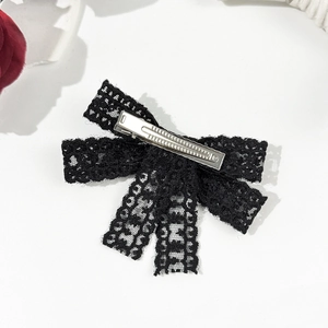 Close-up of black lace bow hair clip with silver metal duckbill clip on white background