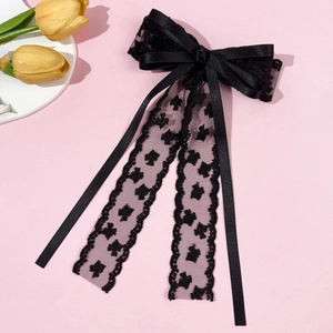 Pince à cheveux élégante en dentelle noire avec rubans sur fond décoratif rose doux