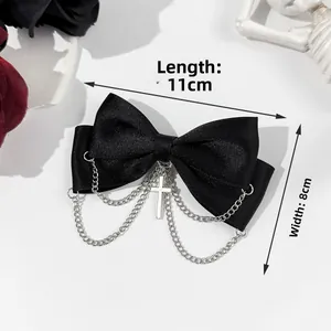 Detail view of black satin bow hair clip with silver metal chains and cross pendant