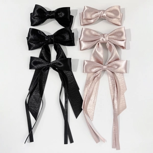Flat lay of elegant satin bow hair clips in black and rose gold with long ribbon streamers