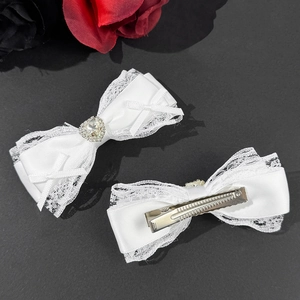 Set of two white satin bow hair clips with lace trim and heart-shaped rhinestones