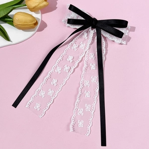 Détail de la pince à cheveux en ruban de satin noir et dentelle blanche brodée