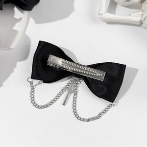Detail of black satin bow hair clip with silver metal cross charm and punk style chains
