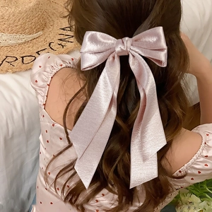 Elegant pink satin bow hair clip with long ribbons for a chic French-style hairstyle