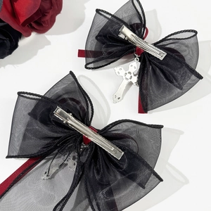 Gothic style bow hair clips with red ribbon and silver cross pendant on white backdrop