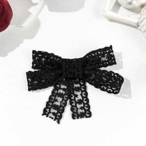 Detailed view of a black lace bow hair clip featuring intricate gothic floral patterns