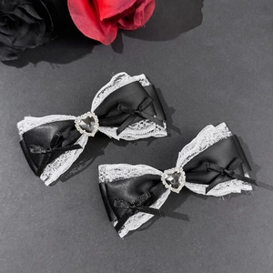 Detail of gothic black lace bow hair clips with heart-shaped black gemstone accents
