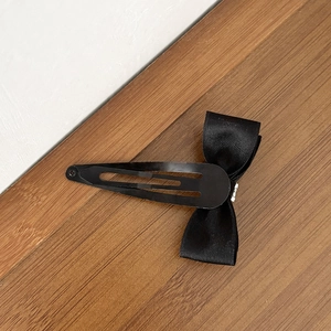 Barrette à cheveux élégante avec nœud en satin noir sur une surface en bois