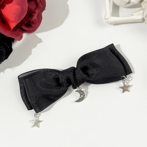 Détail d'une pince à cheveux avec nœud en satin noir et breloques lune et étoile argentées