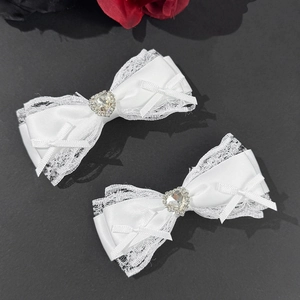 Elegant pair of white satin bow hair clips with heart crystal centers and lace edges