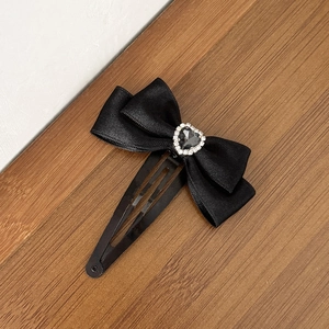 Barrette à cheveux avec nœud noir élégant et strass en forme de cœur sur bois naturel