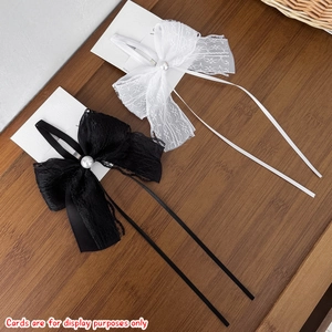 Detailed close-up of lace bow hair clips with pearls and ribbons on display card