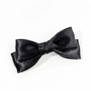 Detail of elegant black satin double bow hair clip with a smooth glossy texture and center knot