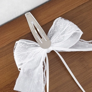 Close-up of white lace bow hair clip showing the metal BB clip and delicate ribbon detail