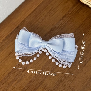 Detail of light blue Lolita bow hair clip showing layered satin lace and pearl fringe