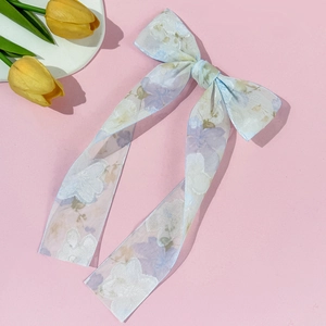 Detail van lichtblauwe bloemen haarklem met grote strik en lange linten op roze decor