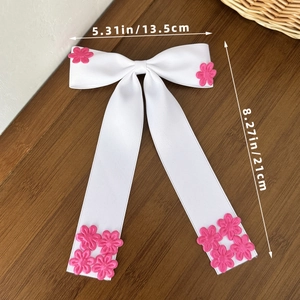 Détail de la pince à cheveux nœud blanc avec accents floraux roses et longs rubans