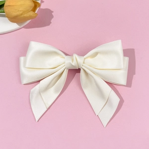 Eleganter cremeweißer Satin-Haarclip mit Doppelschleife auf einem rosa Hintergrund