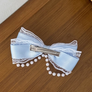 Light blue satin Lolita hair bow with lace edges and pearl tassel on wooden background