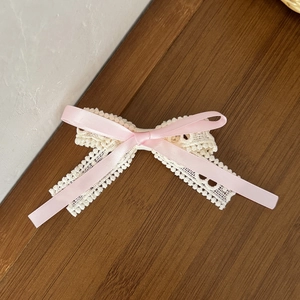 Pink satin bow with beige crochet lace hair clip on dark wood background