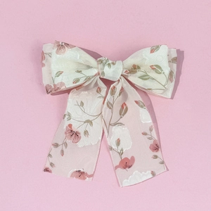Détail d'une pince à cheveux à nœud floral avec fleurs roses sur tissu blanc