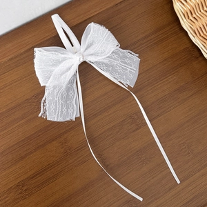 Sweet white lace bow hair clip with faux pearls and long ribbons on dark wood surface