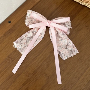 Fermaglio per capelli a fiocco rosa floreale con nastri su una superficie in legno