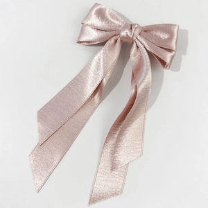 Detail of the elegant satin champagne pink bow hair clip with long flowing ribbons