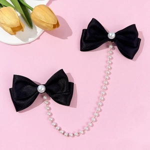 Detailed view of black satin bow hair clips with large center pearls and elegant pearl chains