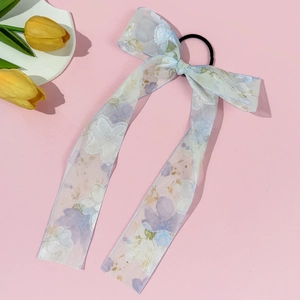 Detail van de bloemige haarelastiek met lange organza linten en een zwart elastiekje