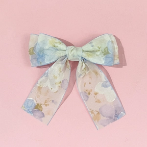 Détail de la pince à cheveux nœud en mousseline fleurie avec bordure bleue et motifs