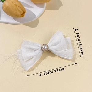 Detail showing the white chiffon bow hair clip with faux pearl and fabric fringe textures