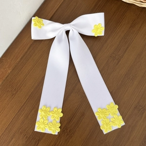 Barrette à nœud en satin blanc avec broderie de marguerites jaunes sur fond de bois