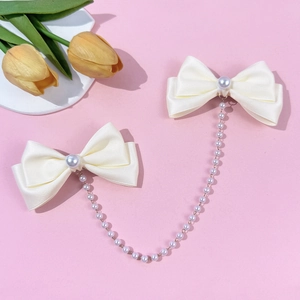 Detail of cream satin bow hair clips with large central pearls and a pearl tassel chain