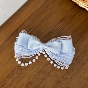 Detailed view of light blue satin Lolita bow clip with white lace and pearl fringe