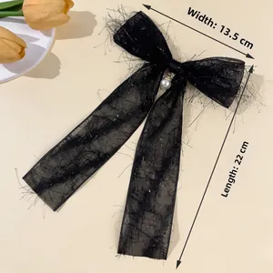 Detail view of a black chiffon bow hair clip with silver silk and a large pearl center
