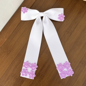 Gros plan d'un nœud papillon en satin blanc avec fleurs violettes sur fond bois