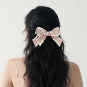 Detailed view of the pink and gold floral embroidery on the butterfly bow hair clip