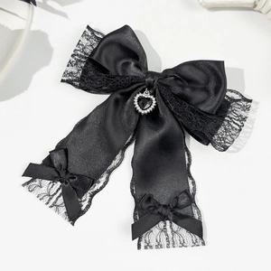 Detailed macro view of black lace bow hair clip with heart-shaped rhinestone charm pendant