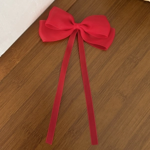 Detail shot of a large red mesh ribbon hair clip with double long streamers on wood background