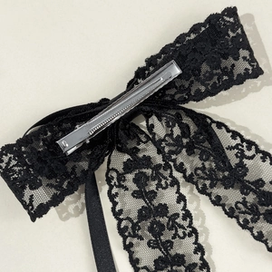 Close-up of black lace bow hair clip showing delicate floral patterns and metal clip