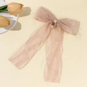 Detail of a pink chiffon bow hair clip with textured fabric and a white faux pearl charm