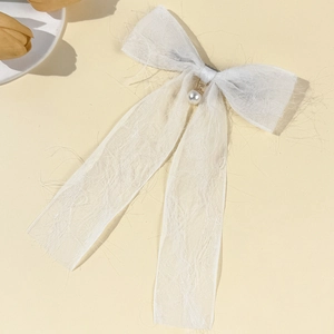 Detailed view of a white chiffon ribbon bow hair clip with a central pearl pendant