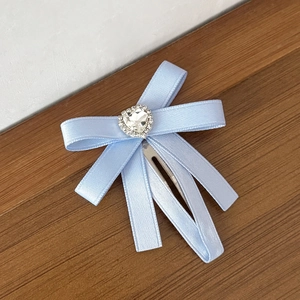 Détail d'une barrette à cheveux en ruban bleu clair avec un grand cristal en forme de cœur