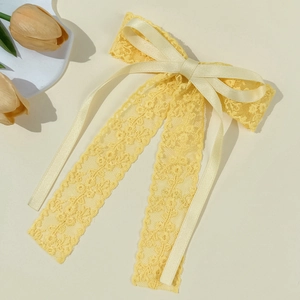 Detail of pale yellow lace bow hair clip with satin ribbons and floral texture