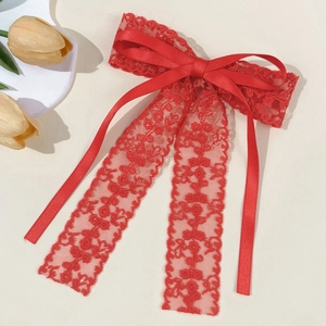 Close-up of elegant red lace bow hair clip with floral patterns and satin ribbon detail